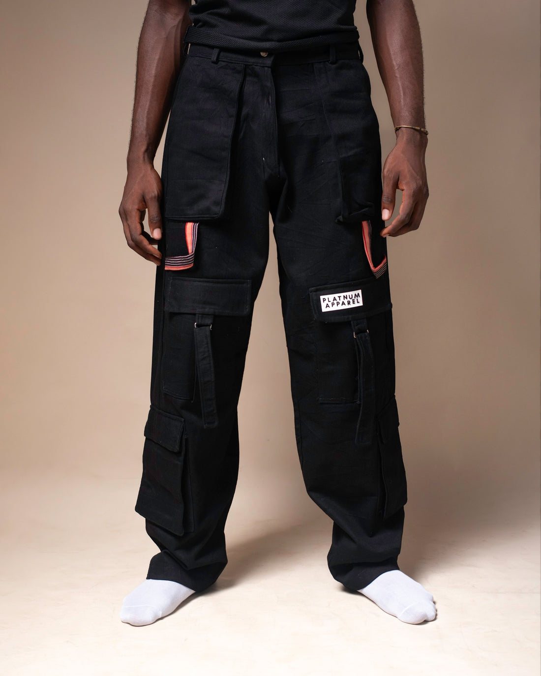 Front view of black men's Cargo Trousers. Stylish and fashionable. With red design detailing and zip closure. Platnum apparel.